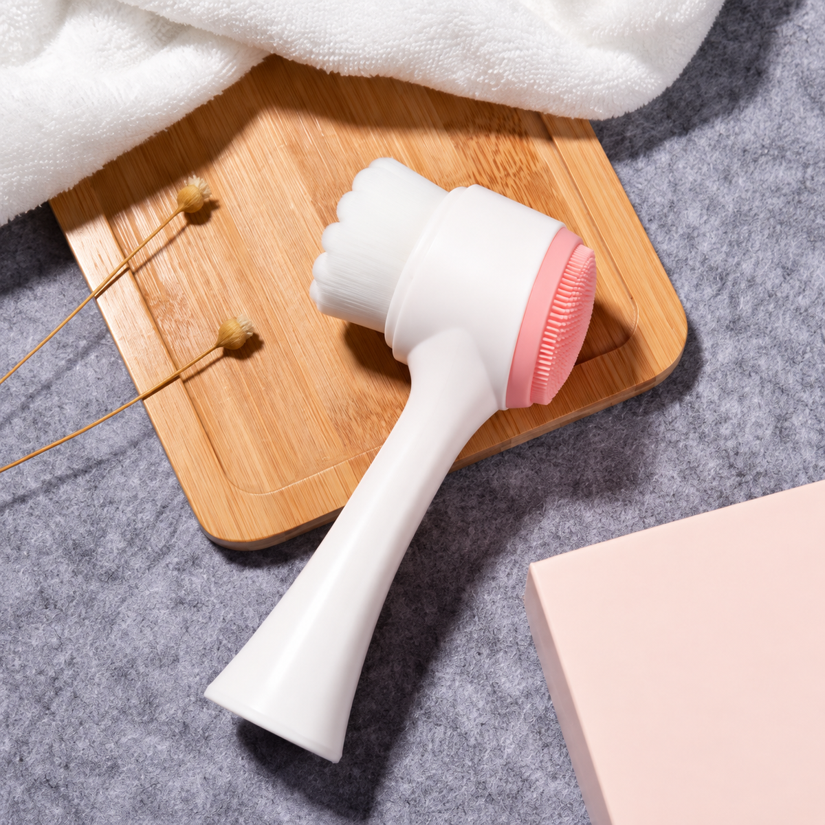 Pink double-sided facial cleansing brush with white handle and bristles